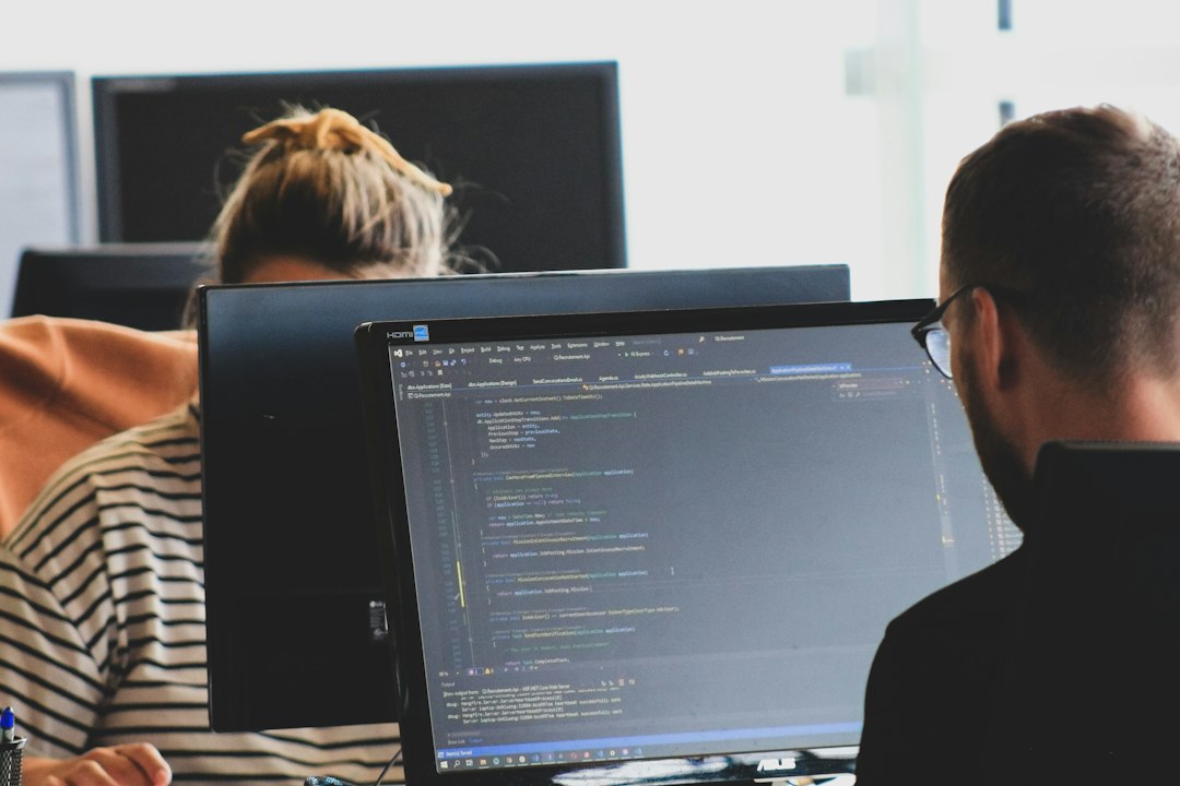 Two team members working on code at monitors in a bright office